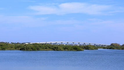 Scenic view of a bridge over water with lush green foliage under a blue sky