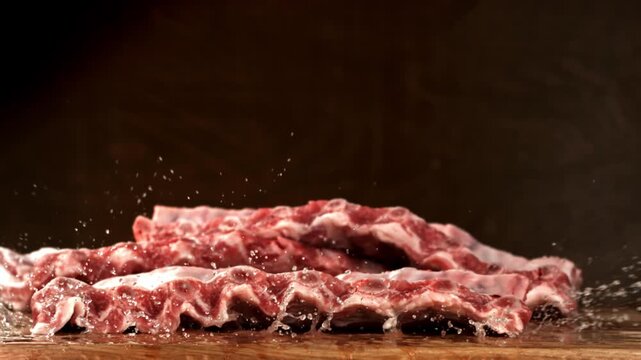Raw pork ribs fall onto a cutting board. Filmed on a high-speed camera at 1000 fps. High quality FullHD footage