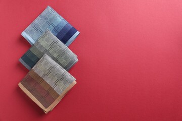 Different stylish fabric handkerchiefs on red background, flat lay. Space for text