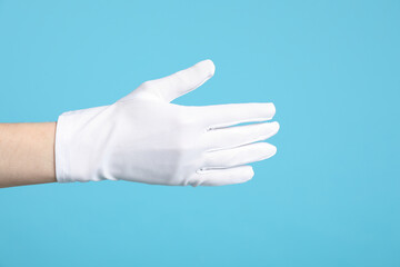 Woman in cloth glove on light blue background, closeup
