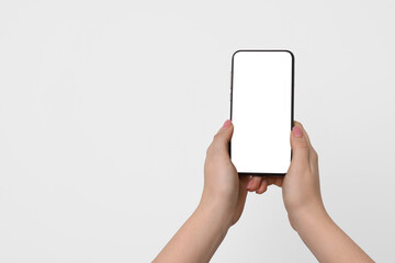 Woman holding smartphone with blank screen on light background, closeup. Mockup for design