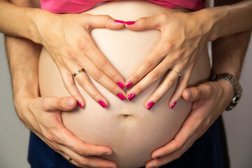 Pregnant Belly With Couple Hands Heart Symbol. Maternity Love And Family Expecting Baby