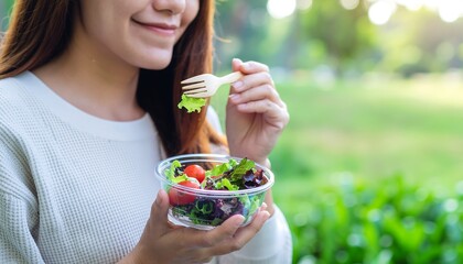 Cheerful woman enjoying healthy salad in sunny park for wellness break
