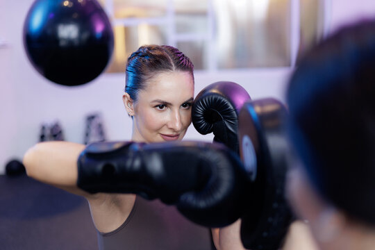 Young caucasian female boxing training in gym, neon light - Powered by Adobe