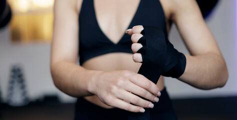 Young caucasian female athlete wrapping hands for boxing workout in gym