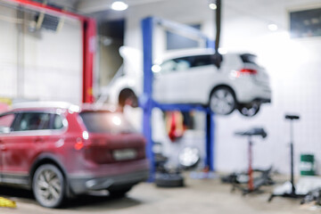 Auto repair shop with cars on hydraulic lifts in blurred background