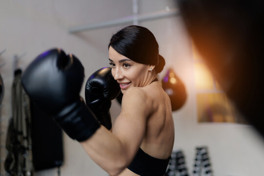 Woman boxing training fighter action, sunlight. Strong young female boxer training with intensity and focus in gym - Powered by Adobe