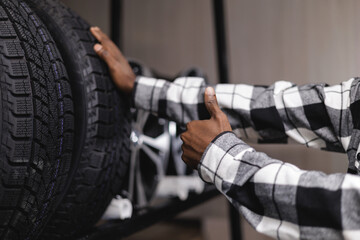 African male checking car tires with thumbs up in store