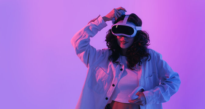 Portrait Young hispanic female enjoying vr experience with headset in neon lighting
