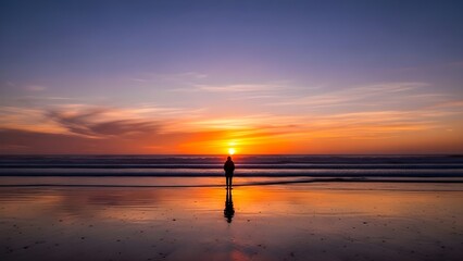 Silhouette of a person standing on a beach during a vibrant orange and purple sunset over the ocean