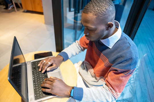 Focused young man working on a laptop in a modern workspace during the daytime