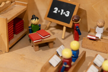 Maquette reconstituant une classe d'&eacute;cole avec des personnages et un d&eacute;cor en bois.