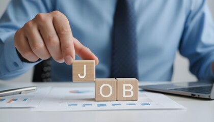 A person's hand places the letter 'J' on wooden blocks spelling 'JOB', symbolizing career and employment opportunities.