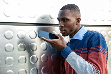 Young man using voice commands on his smartphone in a modern urban setting