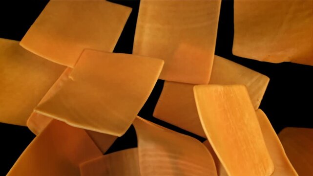 Sliced cheddar cheese flies on a black background. Filmed on a high-speed camera at 1000 fps. High quality FullHD footage