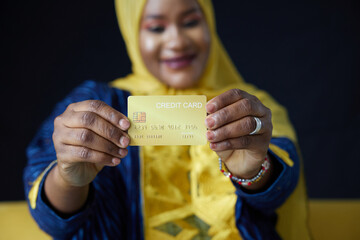 Muslim woman holding a credit card on black background