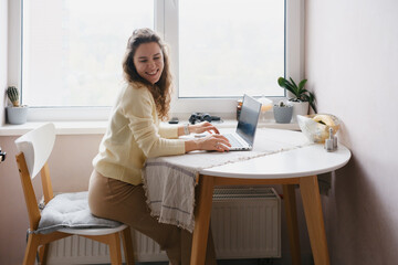 Female professional working from home at round desk with computer, freelance or remote job concept in minimalist modern workspace