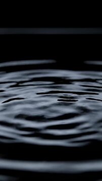 Slow motion close up of perfect concentric water ripples spreading outward on a pristine black surface simulating an echo effect atmospheric, clear, abstract