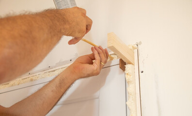 Worker spray construction foam between new door.
