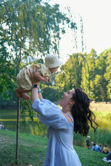 Mother Lifting Baby Outdoors in Sunny Park Happy Time