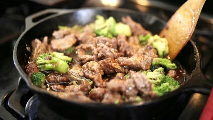 Woman cooking frying meat and vegetables in wok pan on kitchen table.  - Powered by Adobe