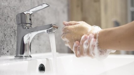 Two hands under running water from a modern faucet, showcasing the importance of hygiene and cleanliness in daily routines, emphasizing health and wellness practices