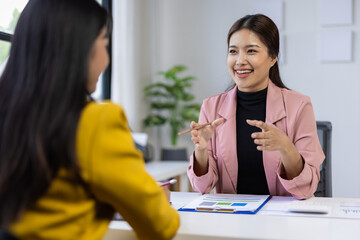 Businesswomen discussing projects together in the office, analyzing documents and charts.