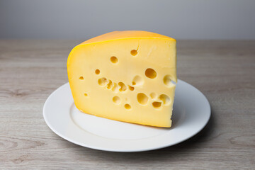 maasdam cheese on a plate, grey background