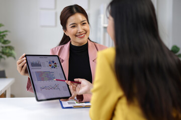 Obraz premium Businesswomen discussing projects together in the office, analyzing documents and charts.