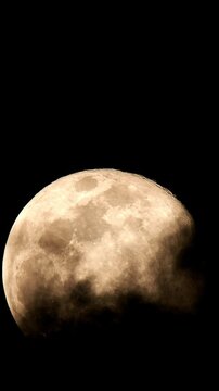 Close-Up of the Full Moon with Visible Lunar Surface and Craters, Partially Obscured by Thin Clouds in a Vertical Frame.