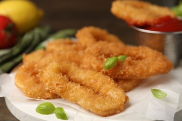Deep fried squid rings with basil and ketchup on wooden table, closeup