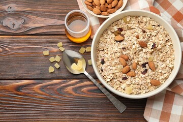 Making granola. Oat flakes, dried fruits, almond nuts and honey on wooden table, flat lay. Space for text