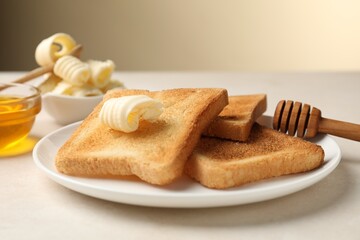 Slices of toasted bread, butter and honey on beige table, closeup