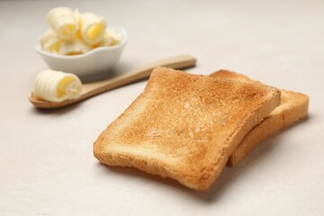 Slices of toasted bread and butter on beige table, closeup