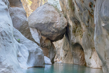 Massive boulder suspended between Goynuk canyon walls, Turkey. Stunning narrow gorge with hanging giant rock above turquoise waters.