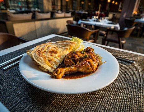 A beautifully styled plate of parotta and chicken is presented on a clean white plate placed over a restaurant table, captured from five distinct professional angles. Each image highlights the rich te