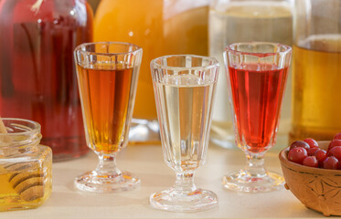 A set of homemade multicolored alcoholic tinctures and liqueurs in bottles and glasses. The bitters. Selective focus