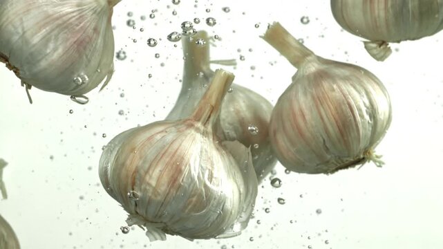 The heads of fresh garlic fall under the water. Filmed on a high-speed camera at 1000 fps. High quality FullHD footage