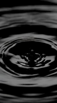 Ultra slow motion close-up of a viscous black liquid surface vibrating and forming symmetrical concentric ripples from low frequency resonance dark, forming, low