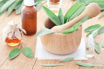 Sage essential oil or water in glass bottles with leaves on wooden table, closeup, copy space,...