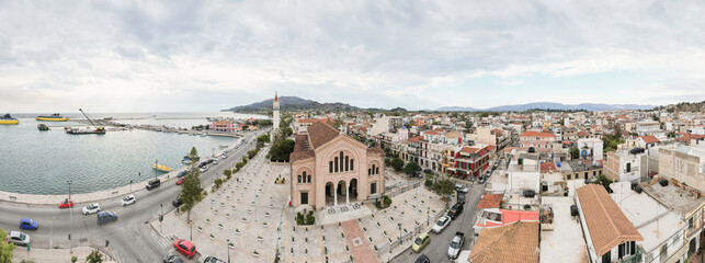 A captivating view of Zakynthos showcases its lively marina, a stunning church, and the bustling...