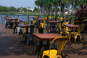Beautiful outdoor landscape of yellow chairs and wooden tables facing a lake. 
