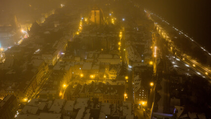 Widok z drona na nocne Stare Miasto w Toruniu, spowite delikatną mgłą. Podświetlone budynki i zabytkowa architektura lśnią w mgiełce, tworząc tajemniczy i nastrojowy miejski pejzaż. © Elżbieta Kaps