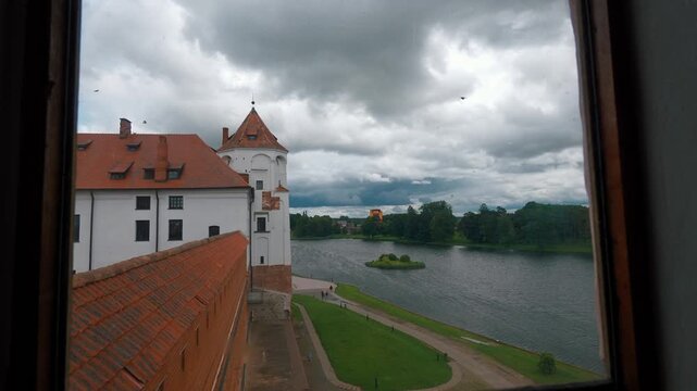 Gradual revealing of the inner courtyard and lakeside of the medieval mir castle complex, a unesco world heritage site in belarus, showcasing its gothic, baroque, and renaissance architecture