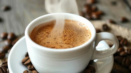A close-up of a steaming white cup of coffee with crema sitting on a saucer surrounded by roasted coffee beans on a rustic wooden surface - Powered by Adobe