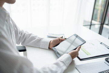 Business man holding digital tablet using Stock market application and reviews finances and manages budget with money cash