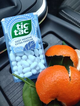 Bo&icirc;te de Tic Tac go&ucirc;t menthe pos&eacute;e dans une voiture avec &eacute;pluchures de mandarine &mdash; photo &eacute;ditoriale
