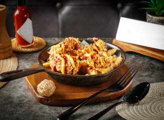 Delectable fried chicken and fries drizzled with savory sauces served in a skillet for a tantalizing restaurant menu or food blog