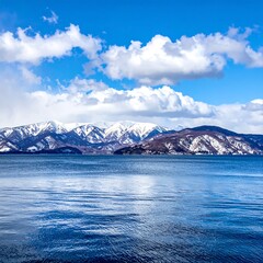 Obraz premium Scenic mountain range meets tranquil lake under a vibrant blue sky