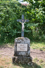 Gott segne unsere Fluren, frommer Wunsch auf einem Stein mit Kreuz am Wegesrand in Bayern © Blende8